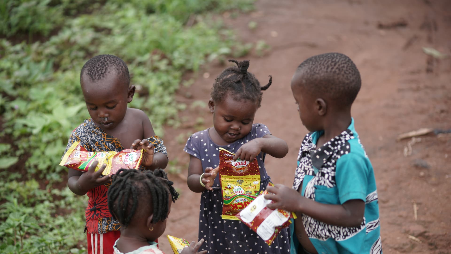 Three young children each holding a JFM food gift box outdoors.