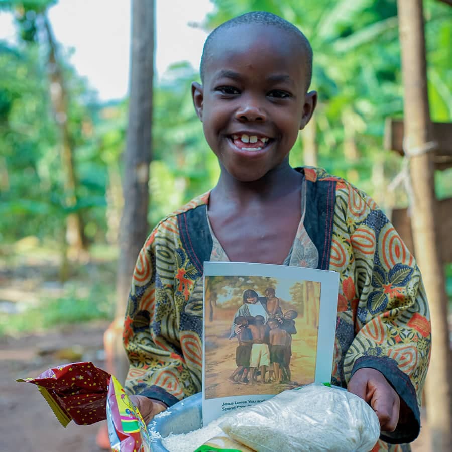 Girl smiling while holding a storybook and a food gift bag.