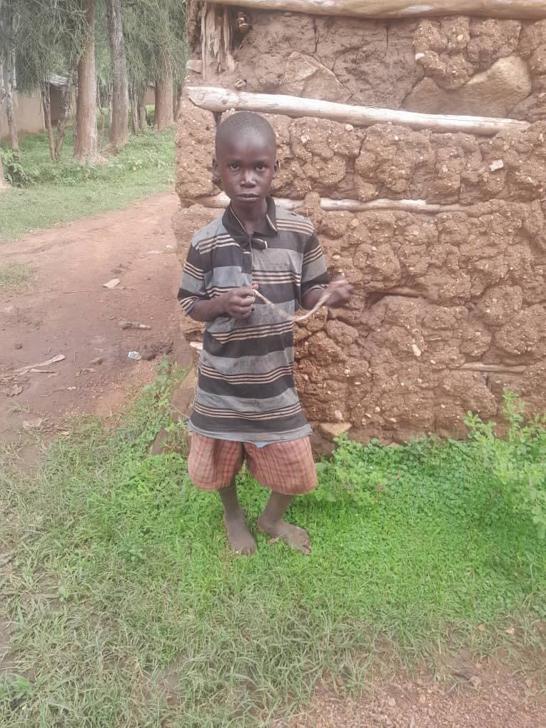 A child stands outdoors near a mud-brick wall during a JFM community visit.