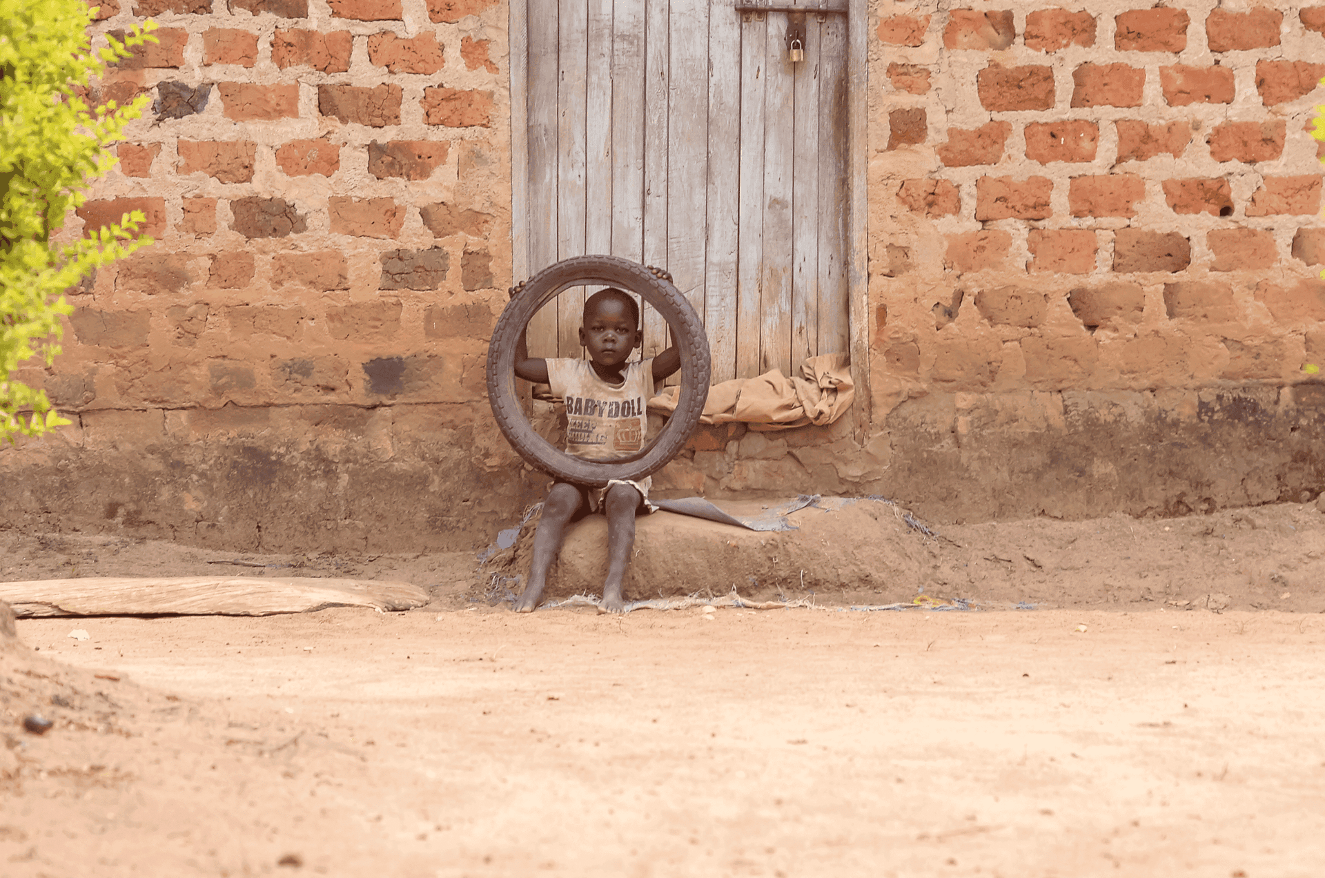 Child sitting in the doorway of a brick building