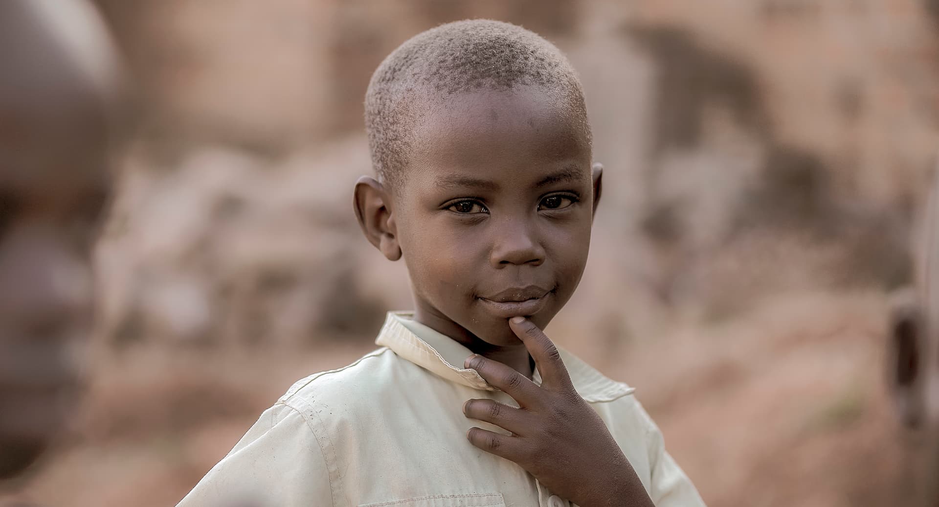 Close-up portrait of a young boy in a white shirt standing outdoors
