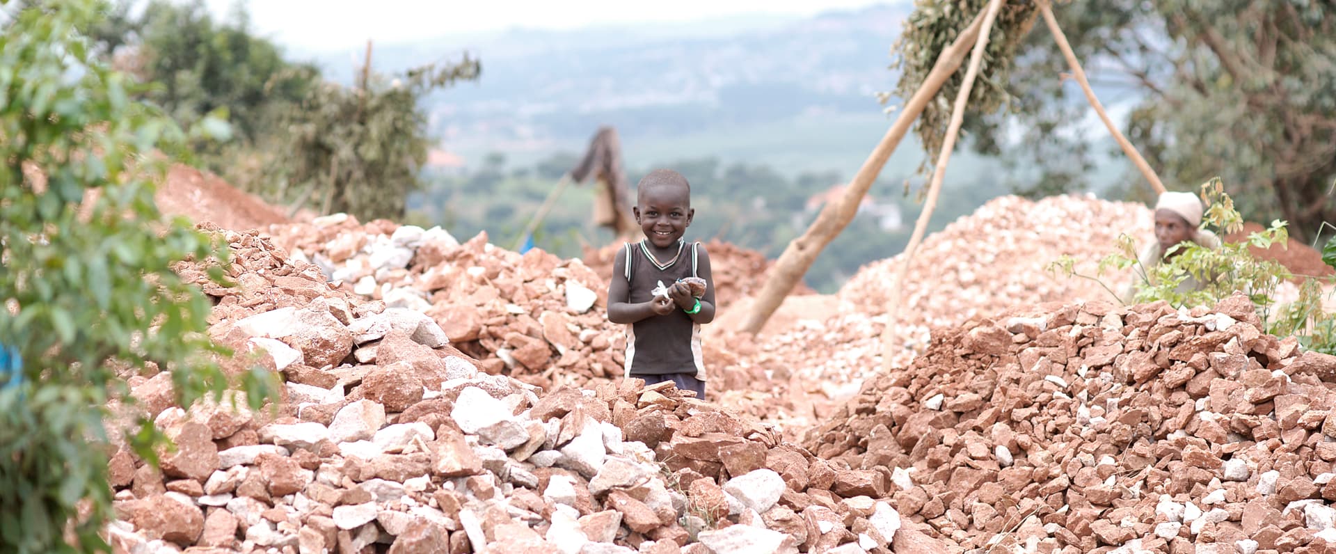 Distant view of a person and child working among piles of crushed rock at a quarry.