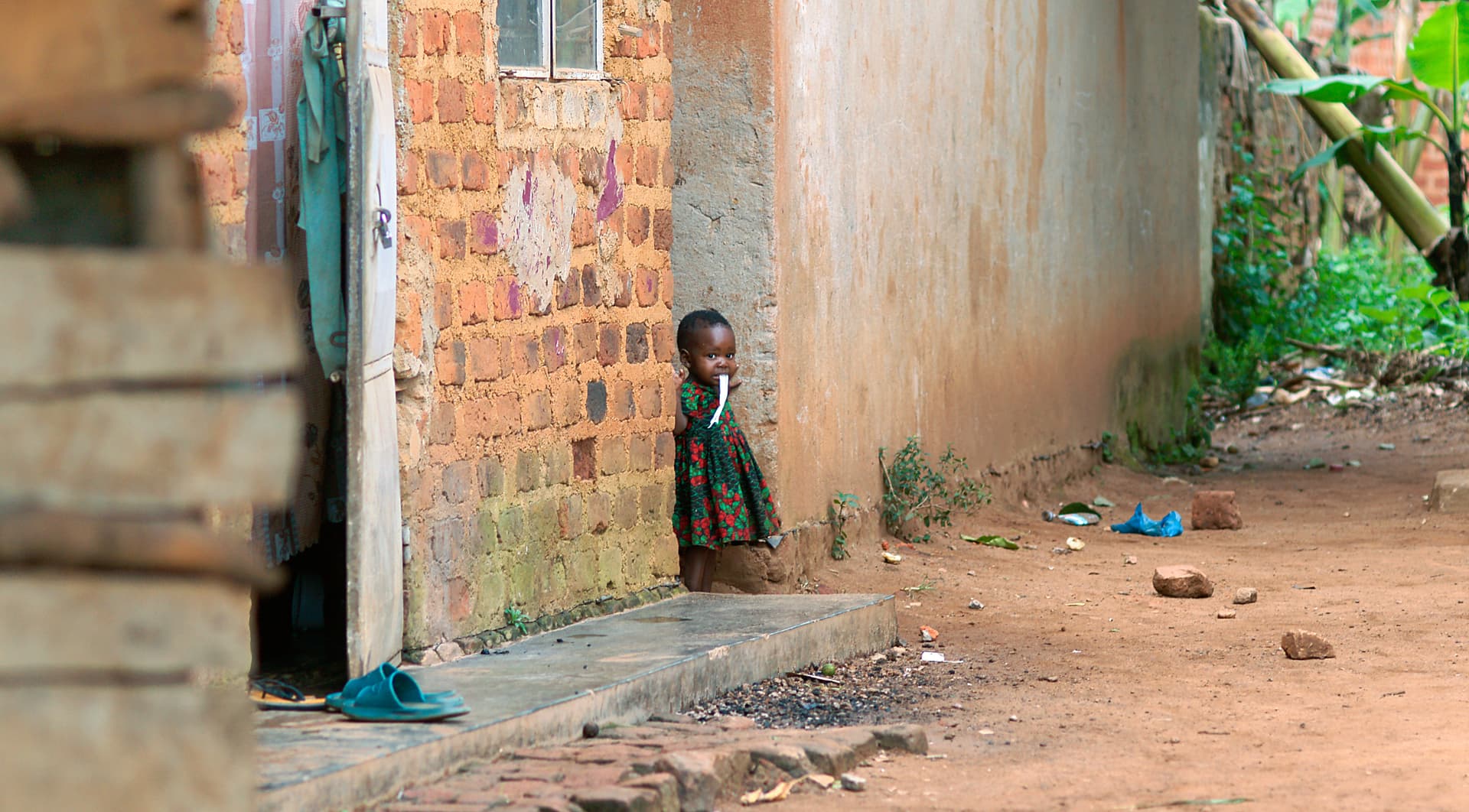 An empty dirt path runs alongside a brick wall in the village.