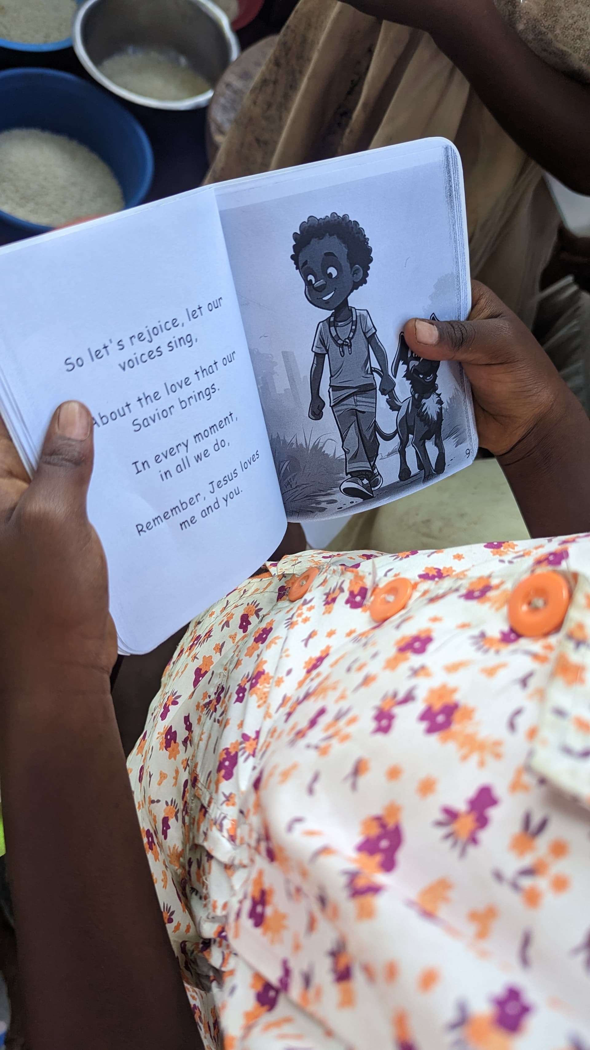 Hands hold open a children's Bible booklet showing an illustrated page.