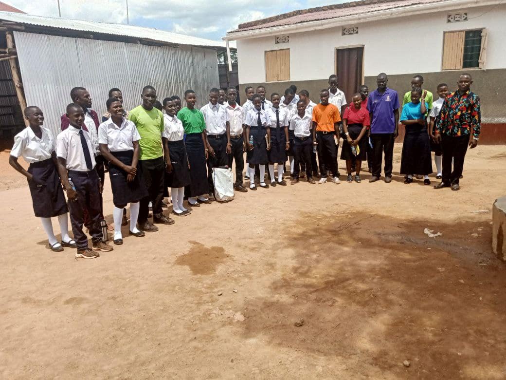 Children in school uniforms stand in a line outdoors near a church building.