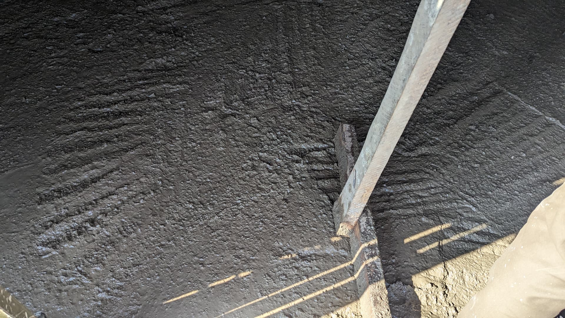 Close-up of a freshly poured wet concrete ceiling slab with rebar reinforcement bars visible.
