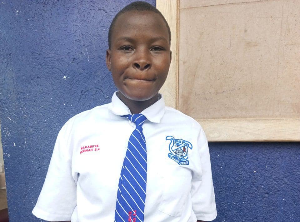 A girl poses for a portrait wearing a white and blue school uniform shirt with a necktie.