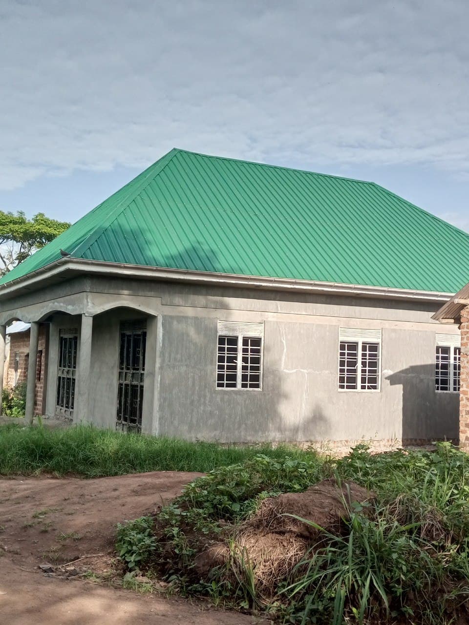 Exterior of a single-story building with a green metal roof and covered porch, likely the Miracle Medical Center clinic.