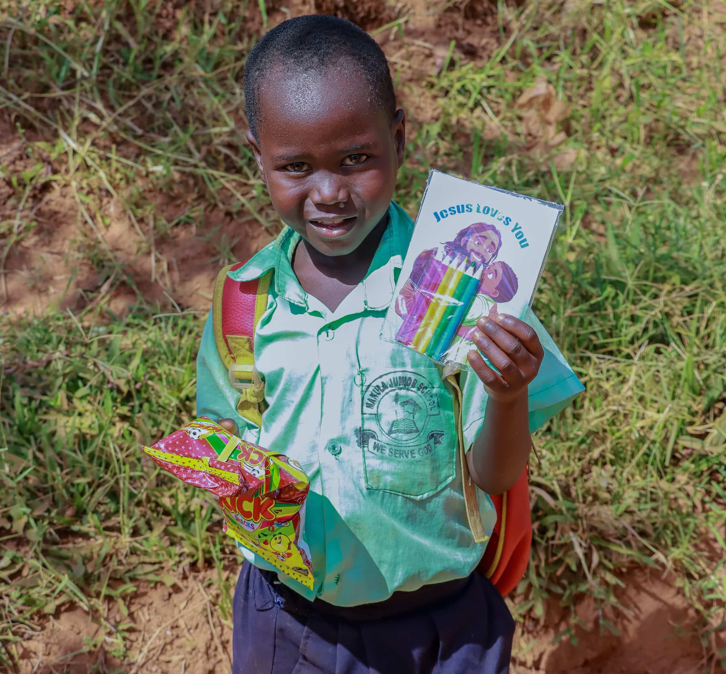 A boy in a green shirt holds several colorful gospel tract booklets outdoors.