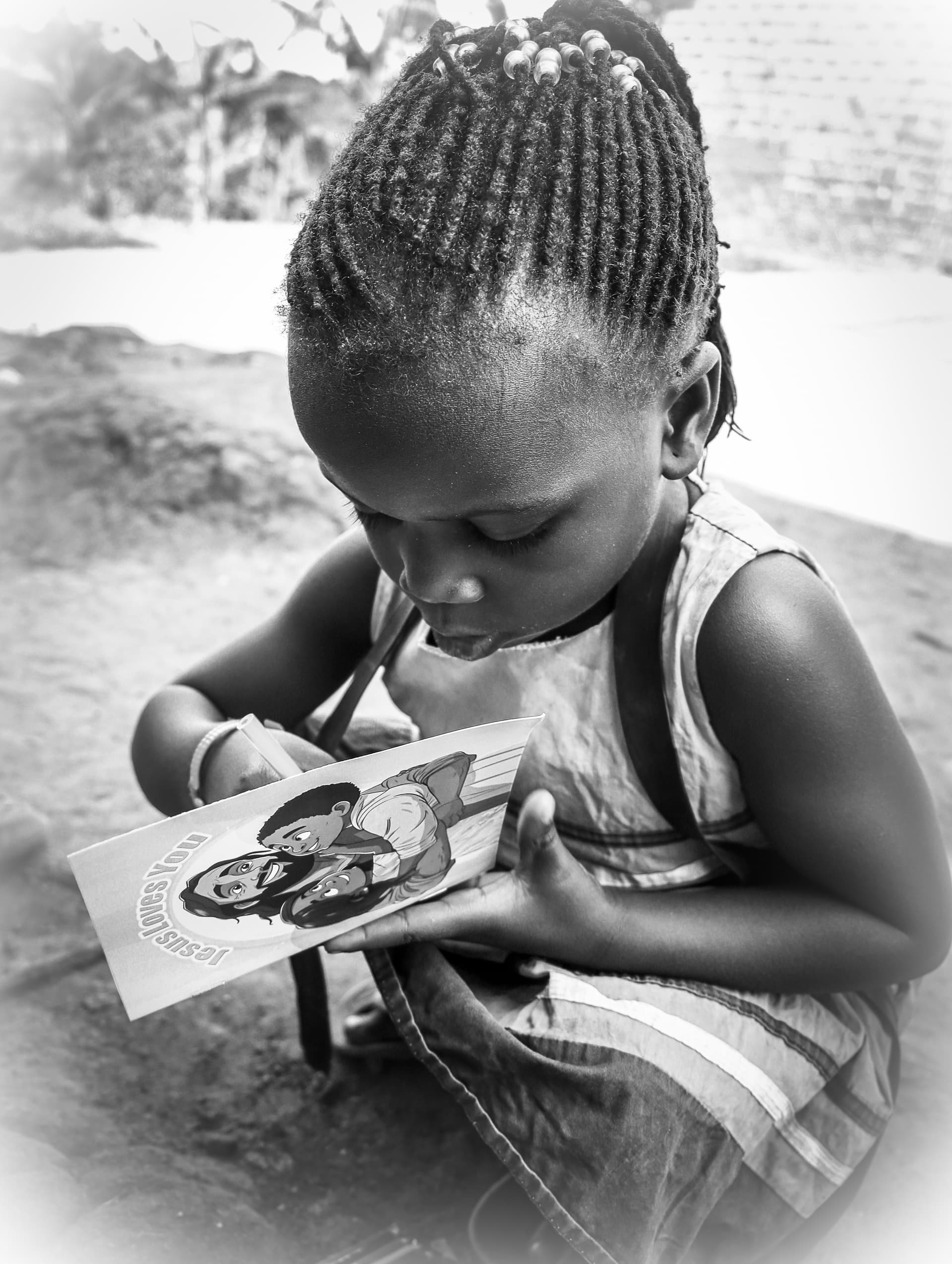 Black-and-white photo of a young child closely examining a small photograph held in their hands.