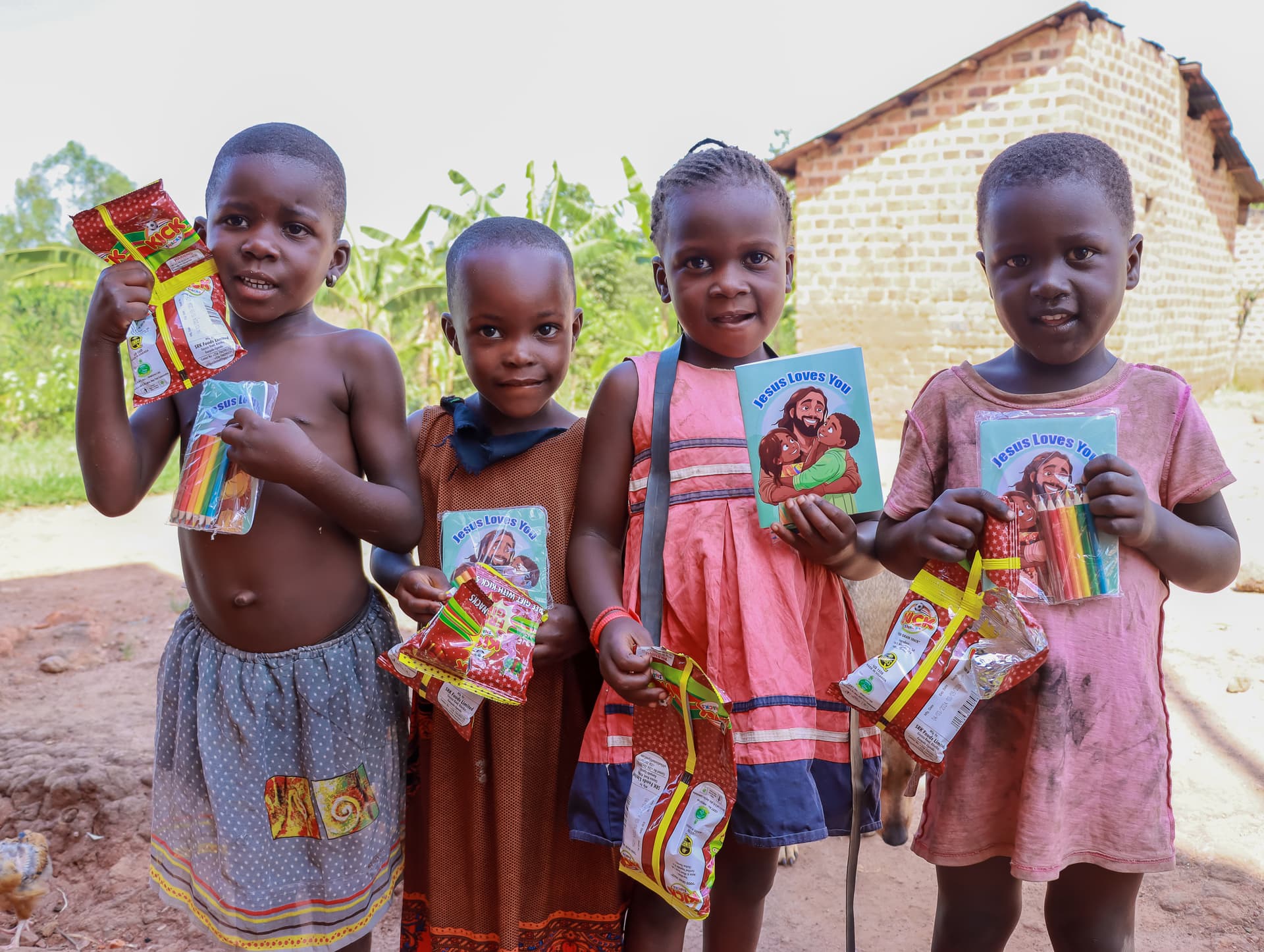 Four children stand together outdoors, each holding a colorful gospel tract booklet.