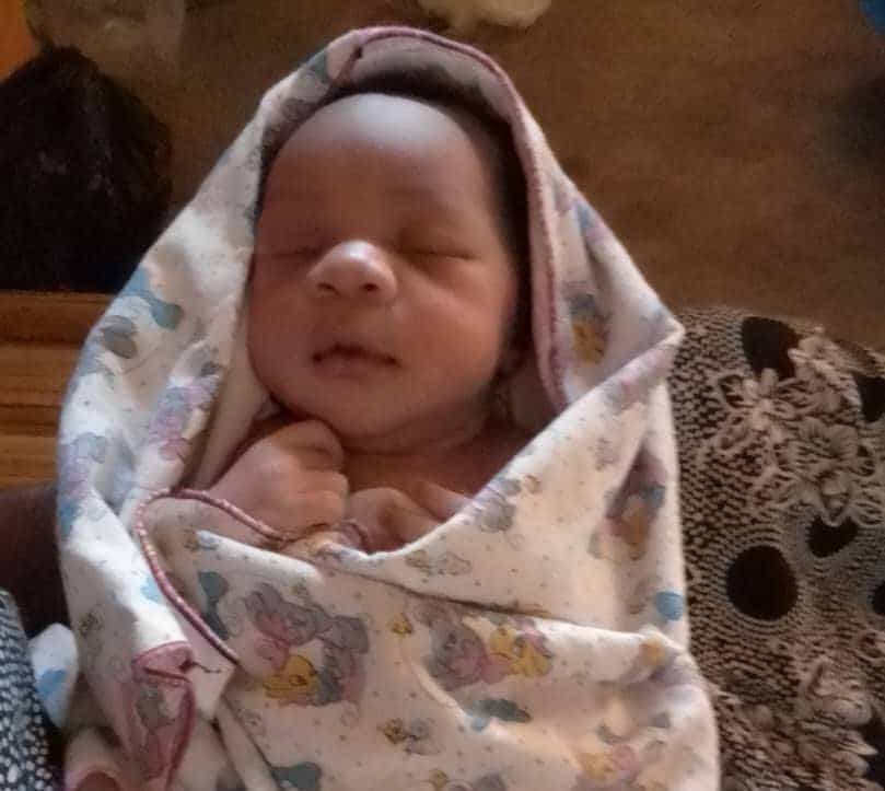 A newborn baby lies wrapped in a patterned blanket with eyes closed, believed to be Sharon's baby.
