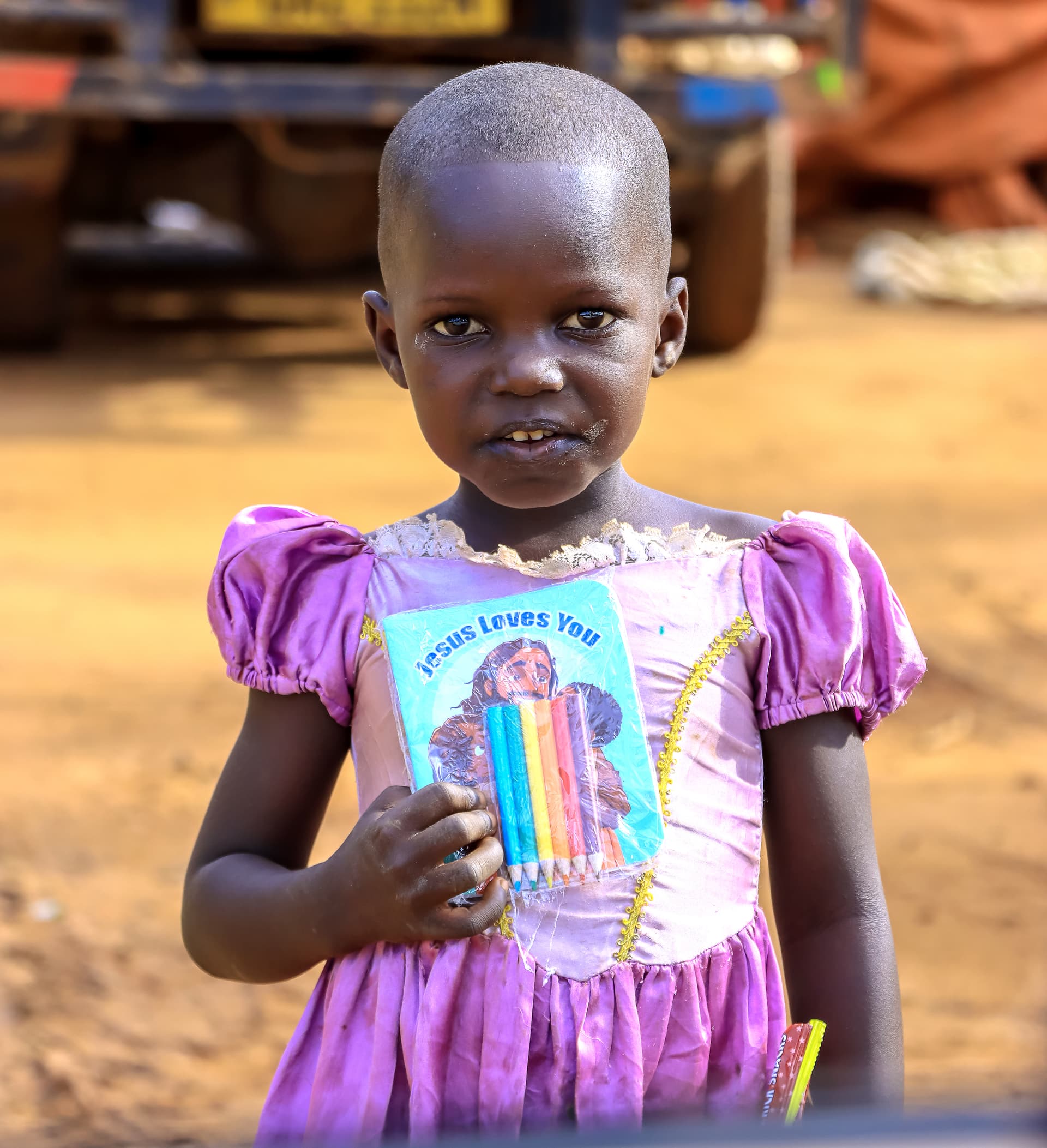 Girl in a purple dress holding a rainbow-covered gospel tract.