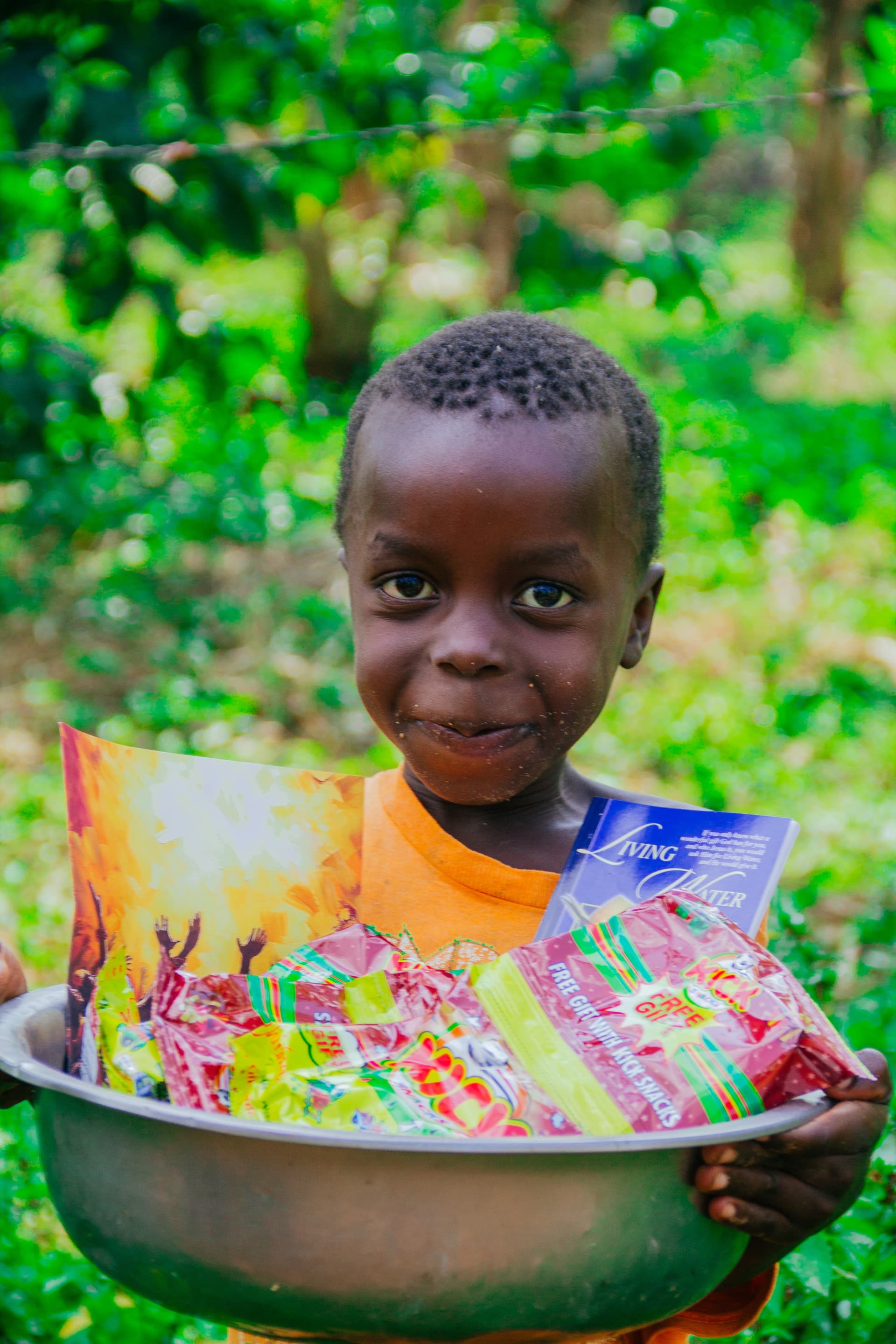 Boy smiling while holding a metal basin filled with snack packets