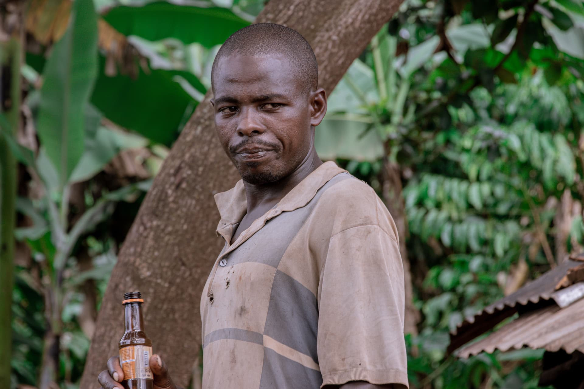 A man standing beside a banana tree, a bottle and gospel tract visible nearby.