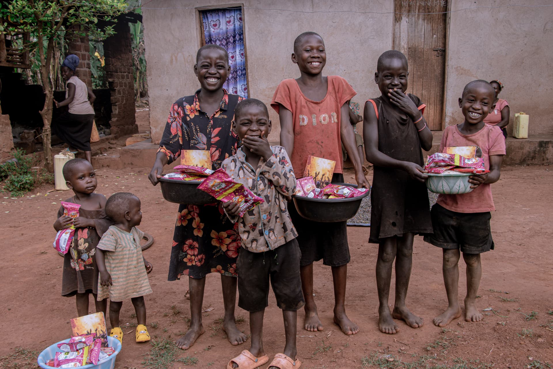 Children in Uganda smiling while holding bowls of food from a Jesus Fed Me delivery