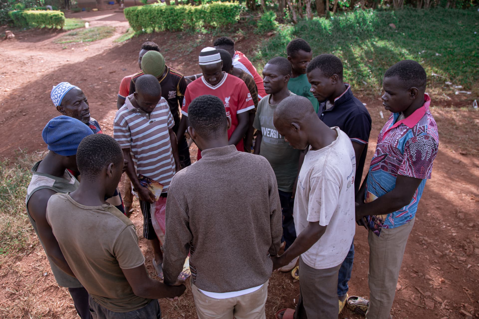Group of young men standing together outdoors on a dirt road.