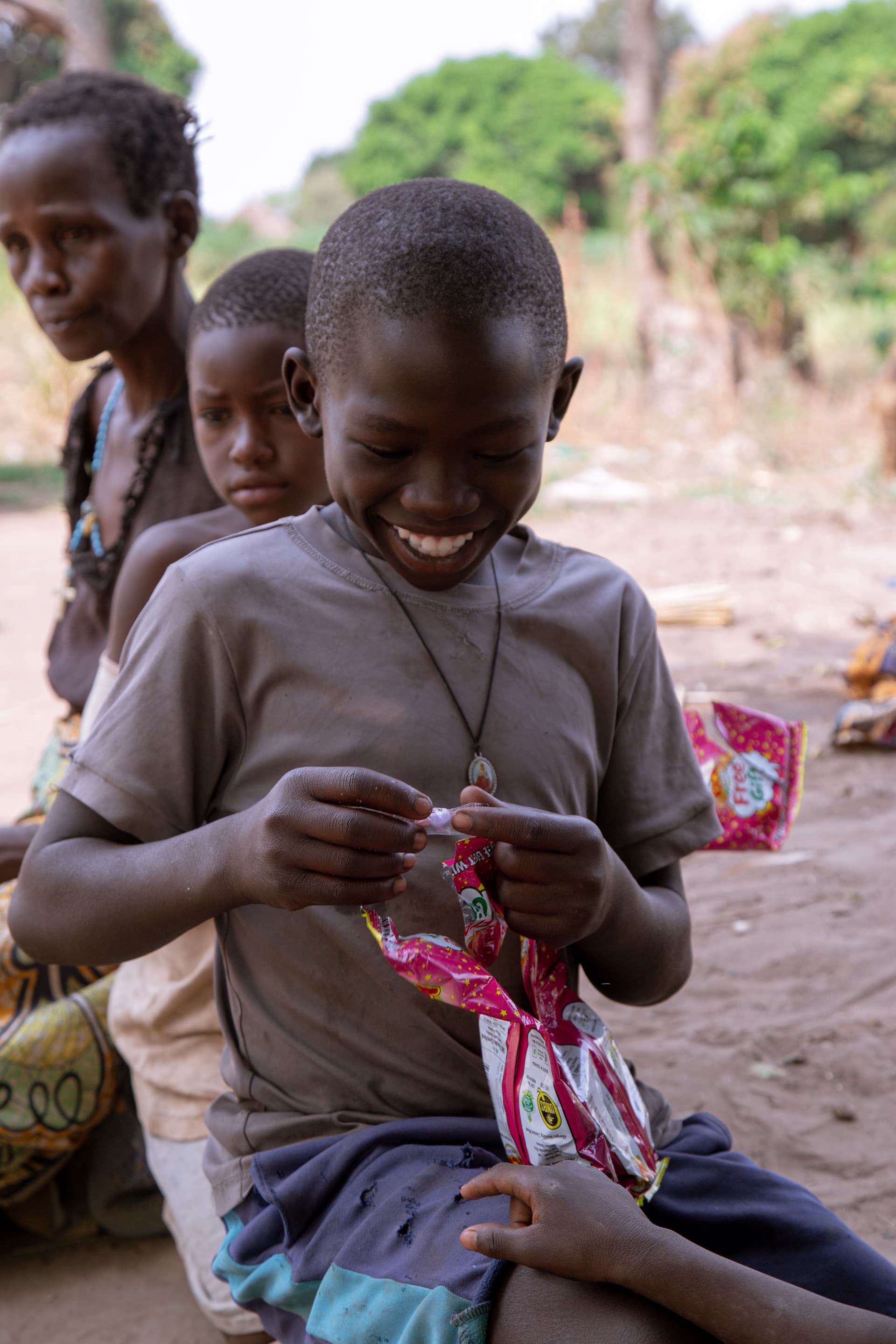 Karamojong children sit together tying on beaded necklaces from a gift package.