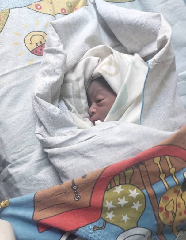 A newborn baby wrapped in blankets rests on a bed at Miracle Medical Center.