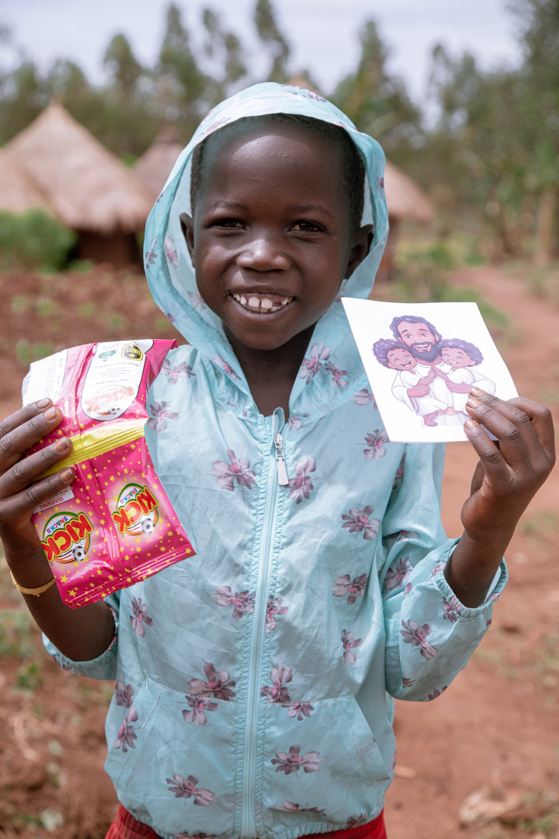 Smiling girl in a mint green outfit holding a photo card and a new clothing item she received.