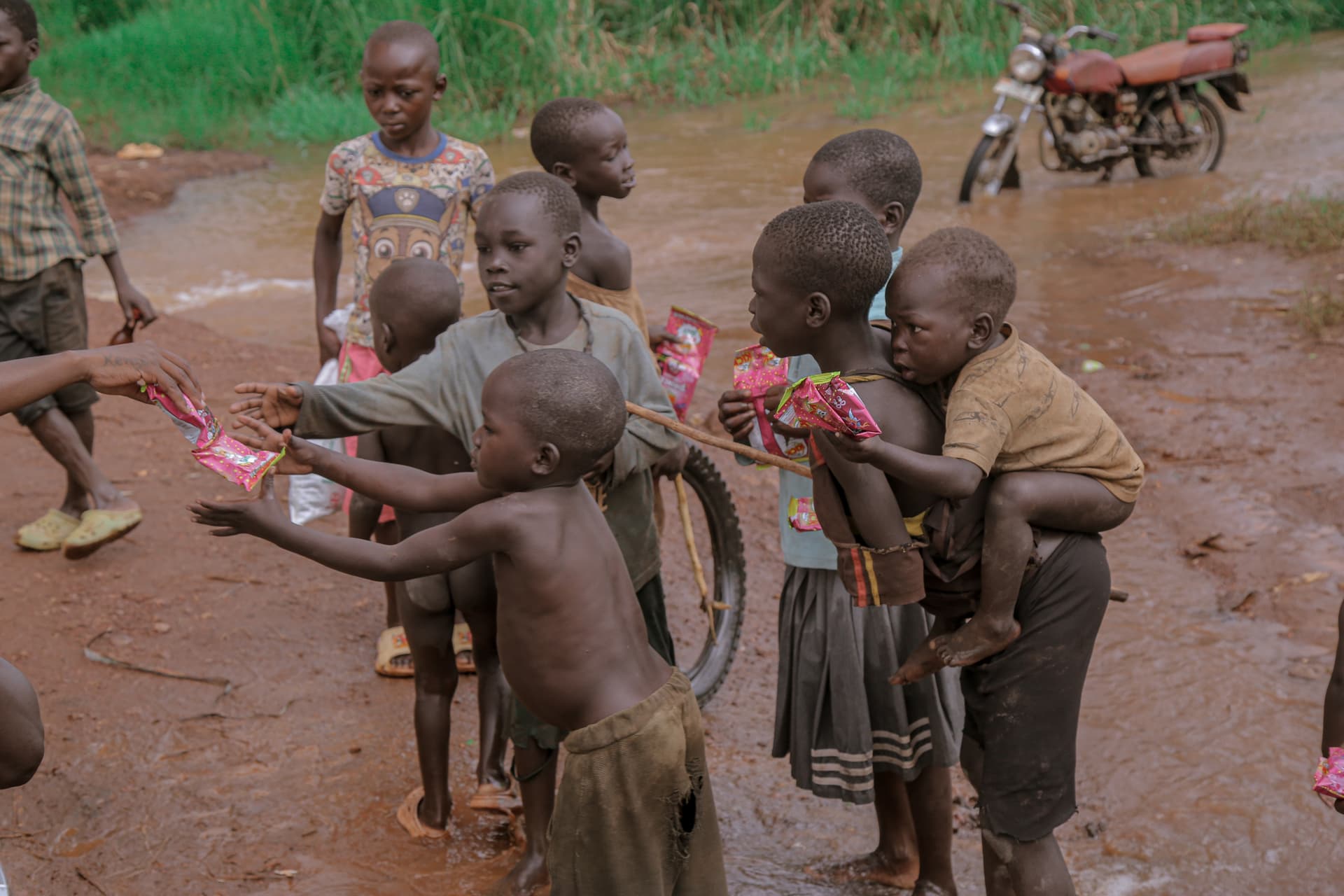 Children reach out to receive pink food gift packets from a distributor.
