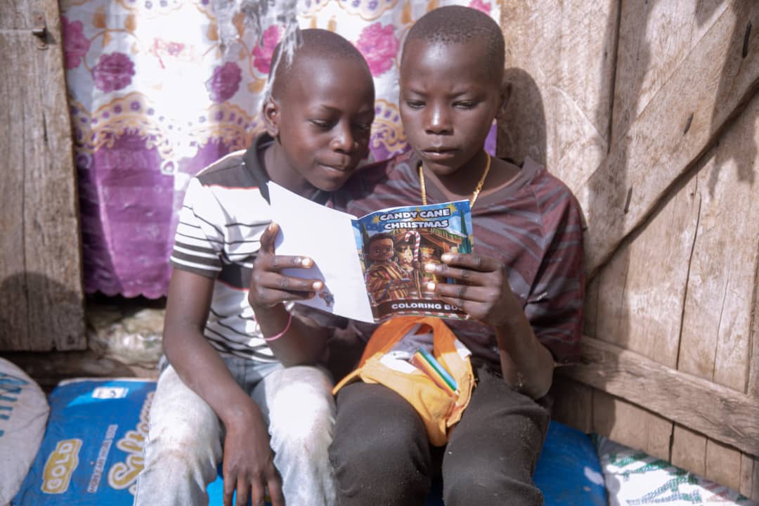 Two children sit together examining a food packet.