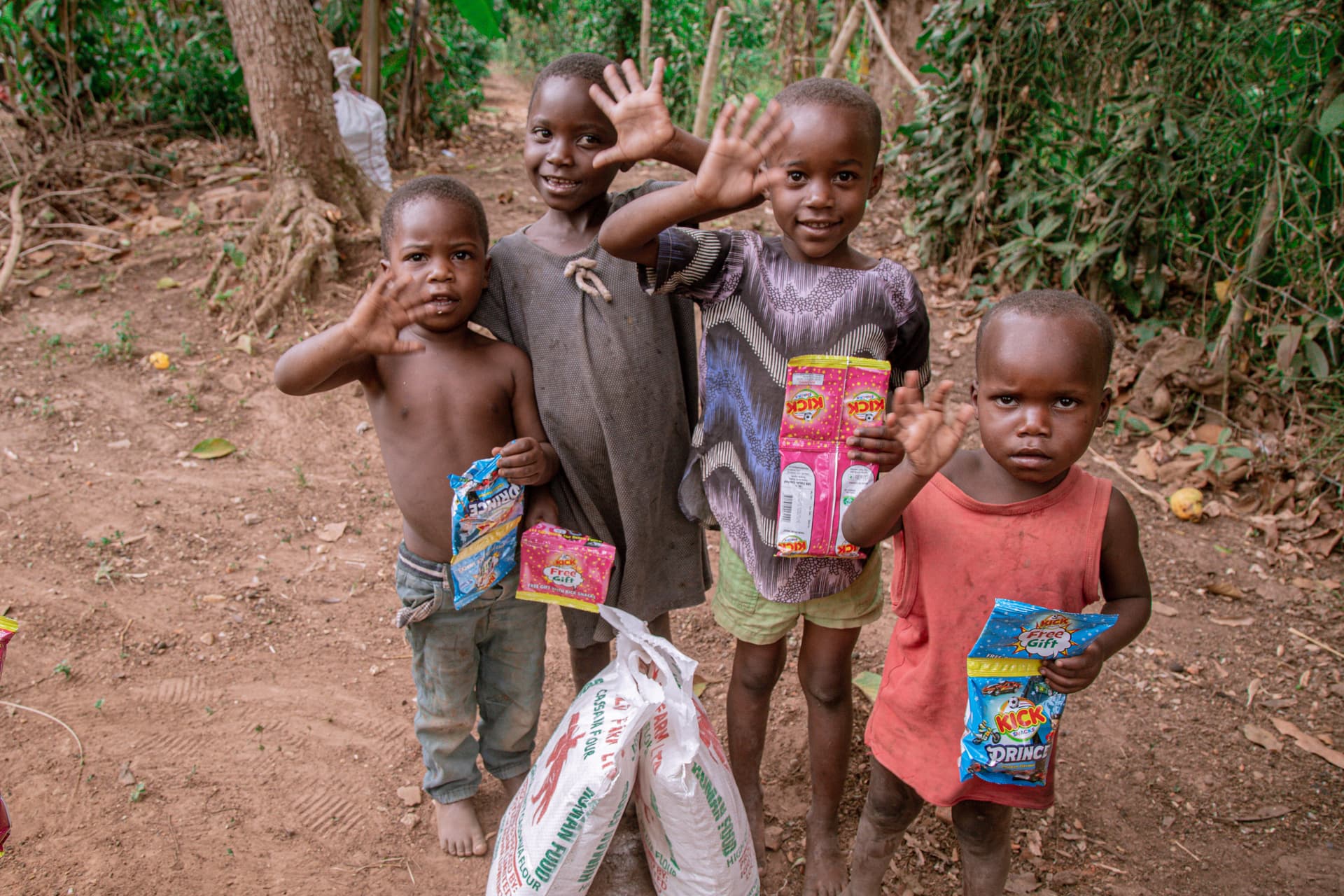 A group of children stand together holding food gift packets and a gospel tract.