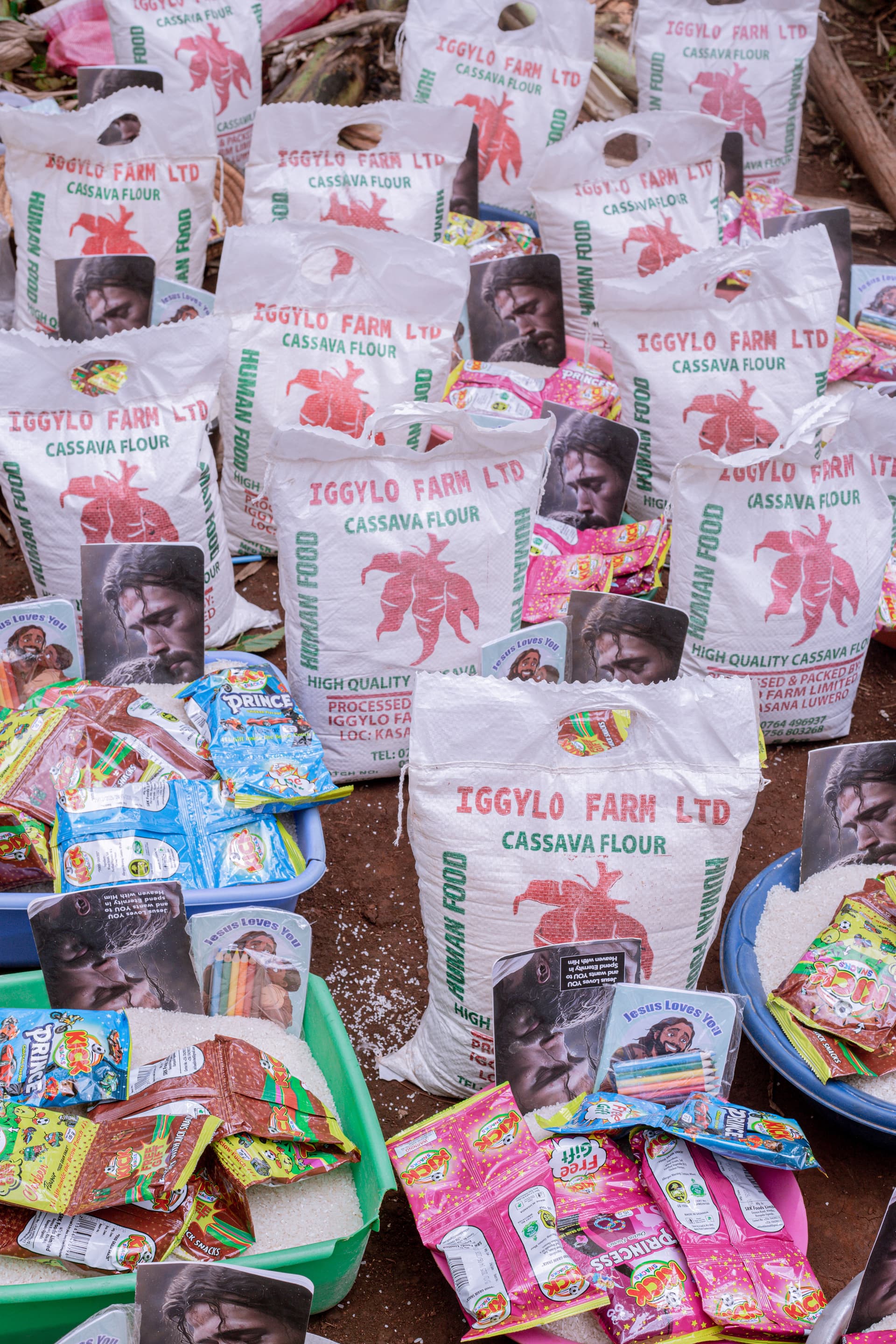 Stacked bags of maize flour and food packages sit beside a printed photo card.