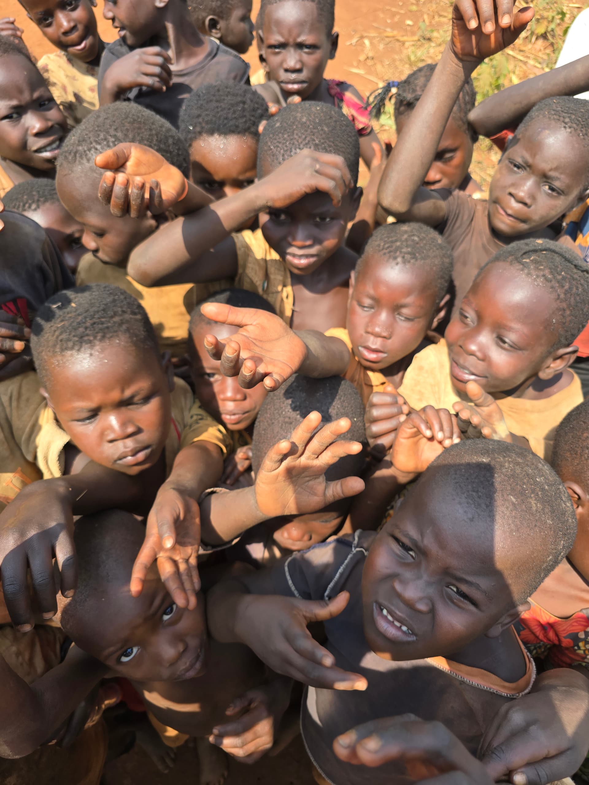Close overhead view of children's hands and faces clustered together during a distribution.