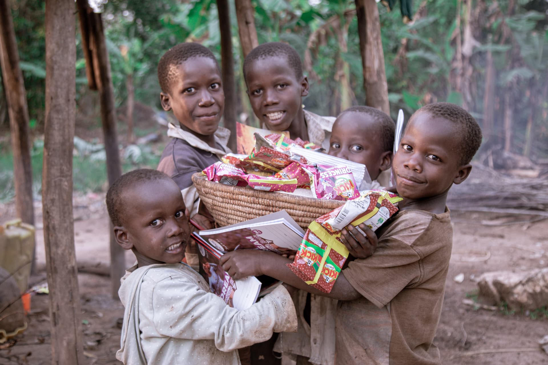 Group of children standing outdoors holding baskets filled with food donation packages.
