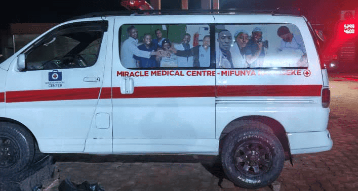 White Miracle Medical Center ambulance van parked at night, marked with a red cross and stripe.