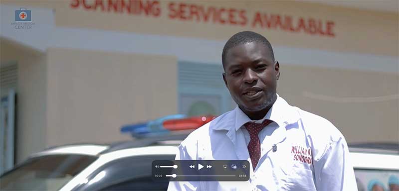 Video still of a man in a white medical coat outside Miracle Medical Center, a scanning-services sign behind him.