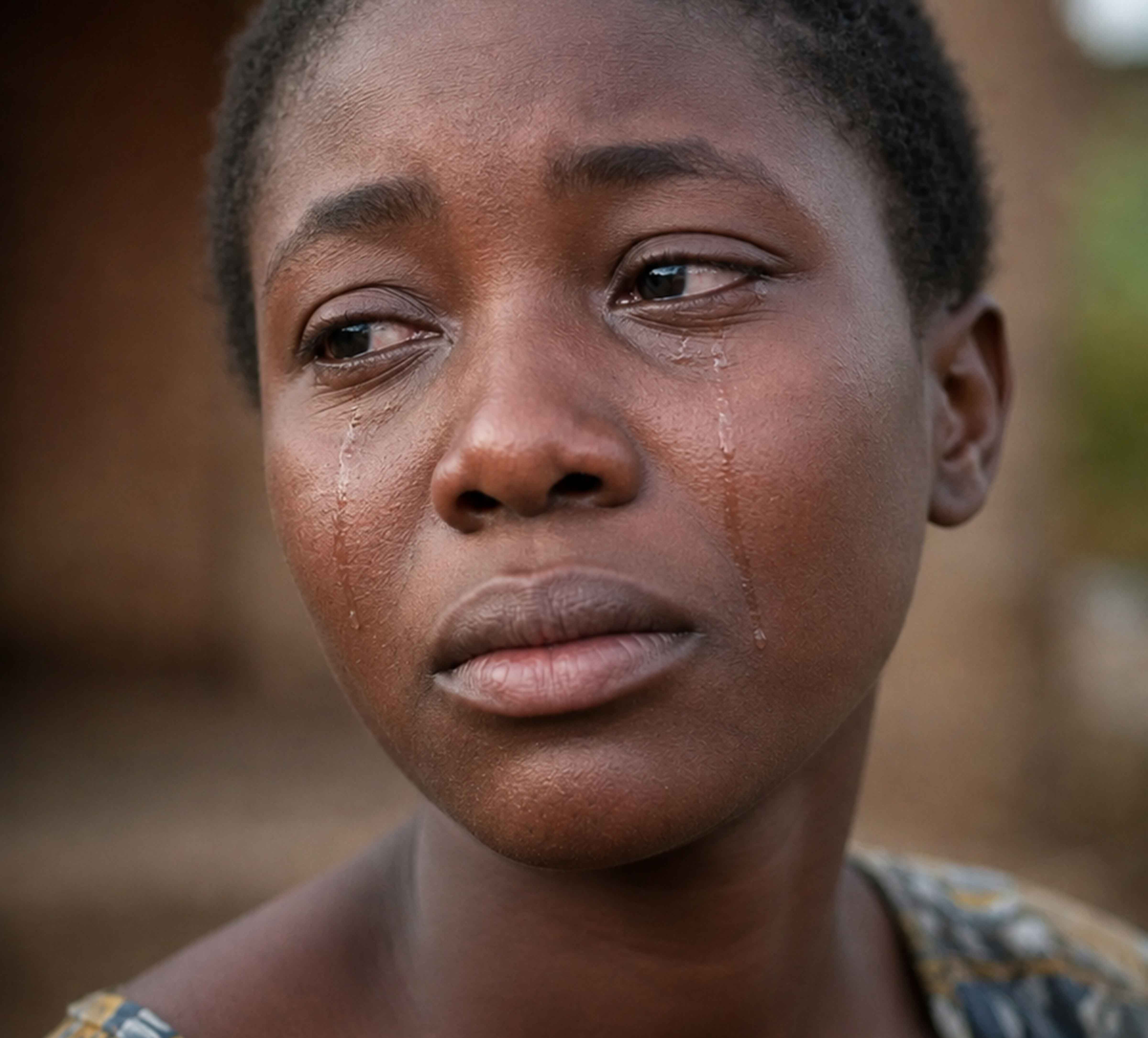 Close-up portrait of a young woman with tears on her cheeks, looking distressed.